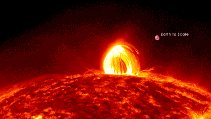 a large fiery loop erupts out of the sun a nearby earth is visible for scale