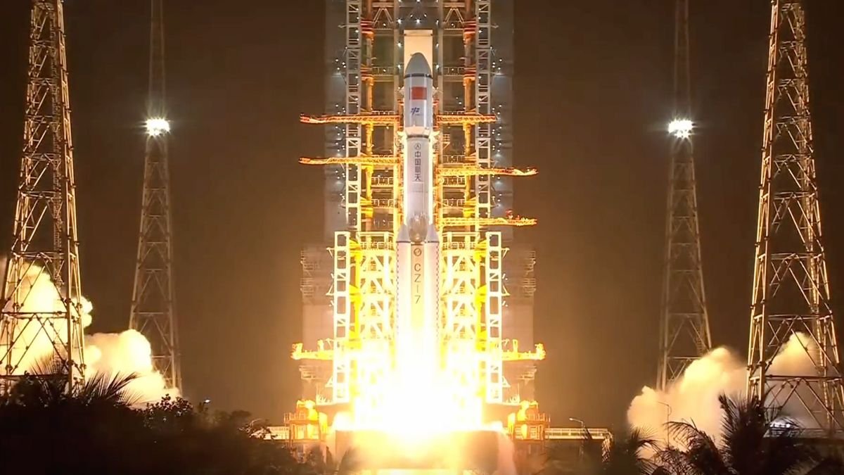 a white rocket rises off its launch pad at night