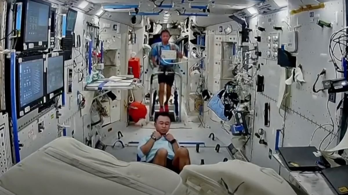 two astronauts exercise inside a white walled space station