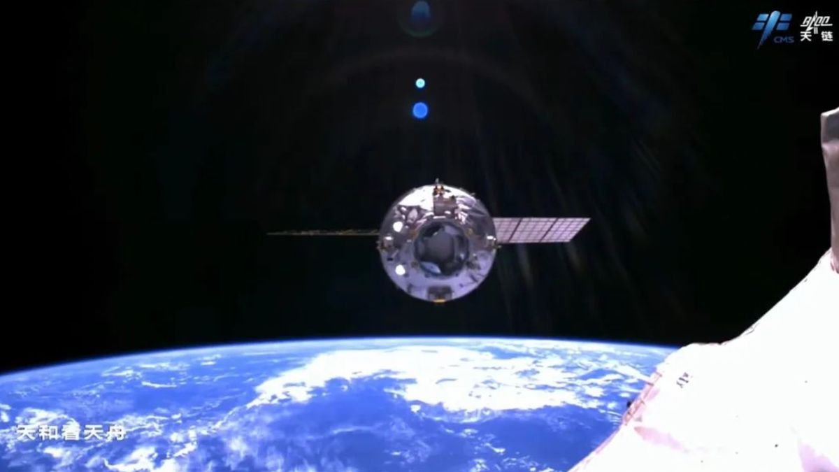 a spacecraft departs a space station with the curve of earth and the blackness of space in the background