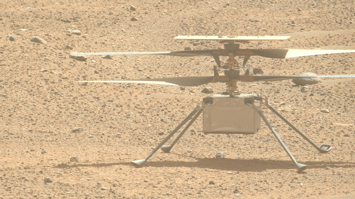 closeup of a four rotor drone sitting on pebbly red dirt