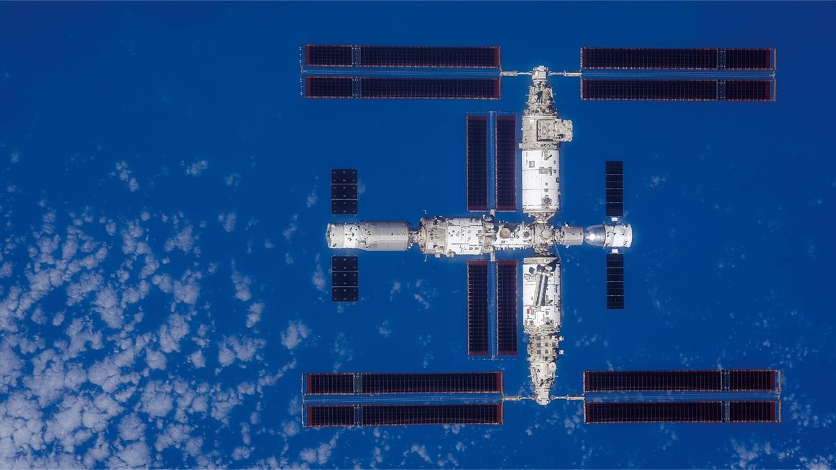 a large T shaped space station is seen from above with Earth below it