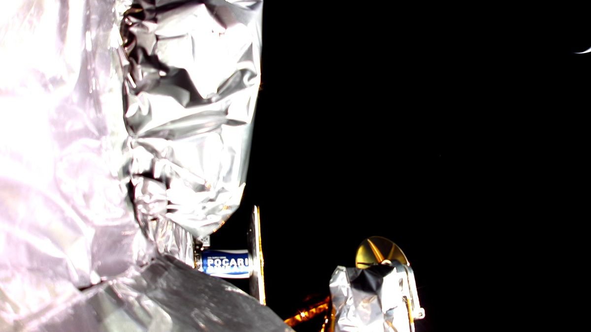 photo showing the silvery insulation of a spacecraft and the blackness of space in the background with a possible sliver of earth in the upper right corner