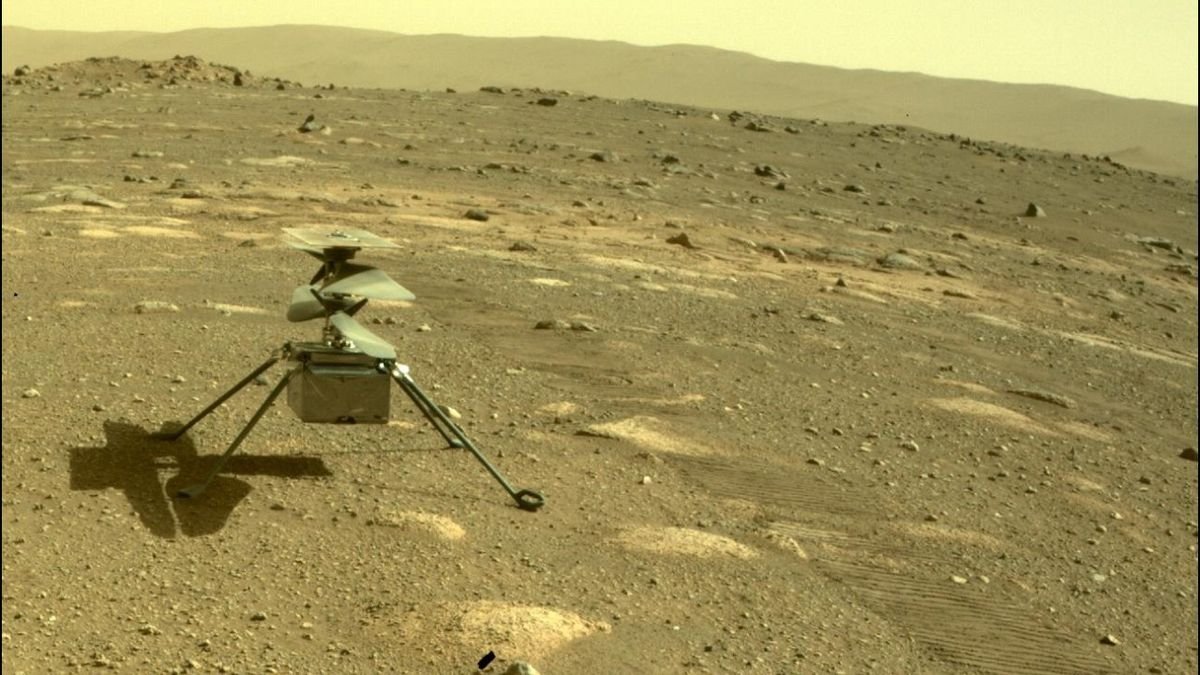 a small helicopter sits in red rocky dirt