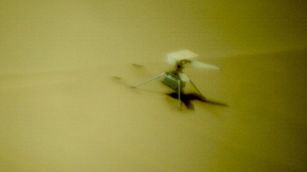 close up view of a small boxy drone resting on a sand dune