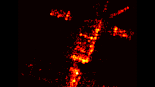 Grainy orange and yellow pixels form the shape of a satellite with various protruding panels and masts against a sky of black
