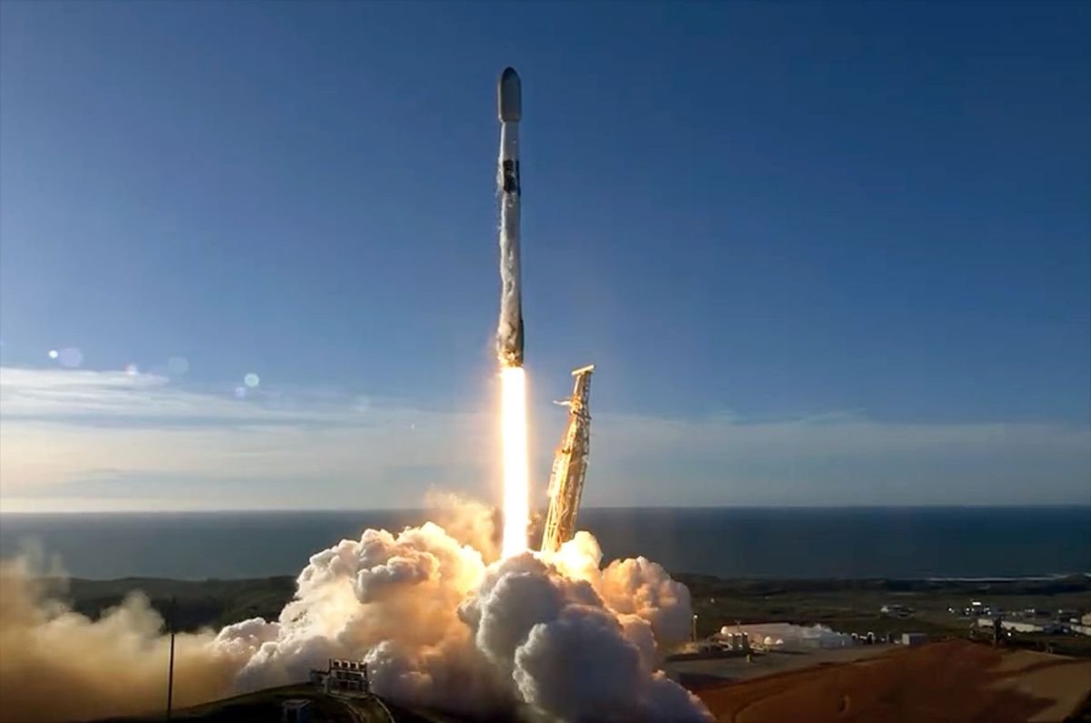 a black and white spacex falcon 9 rocket launches into a blue sky