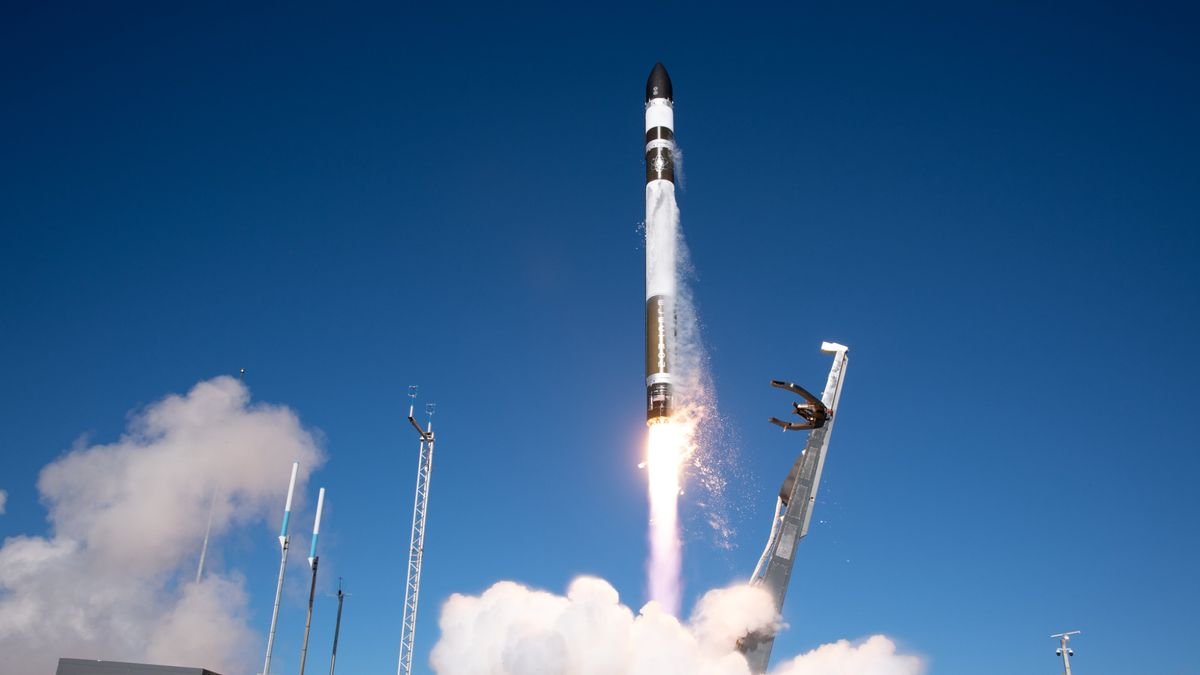 a white green and red rocket launches into a blue sky