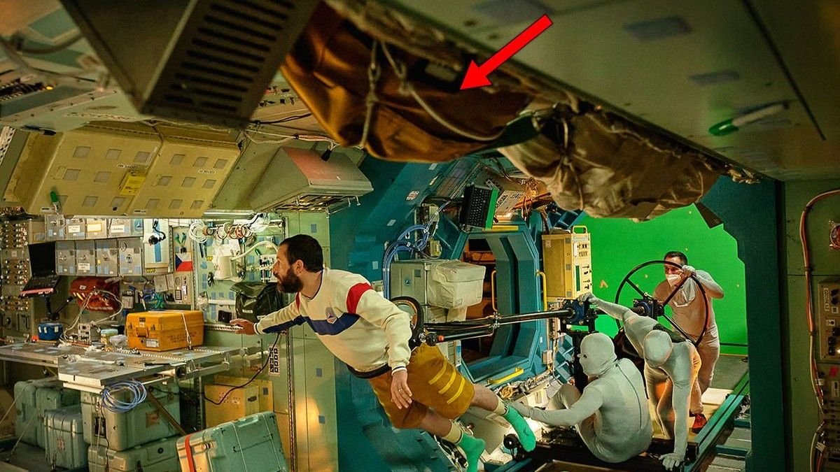 on a movie set an actor is held aloft by a crane to make him look as if he was floating in a cramped space station corridor