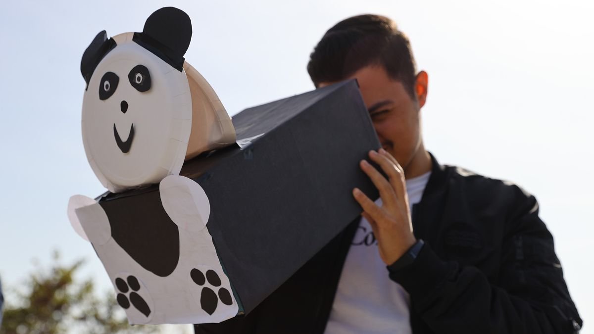 a man looks through a pinhole projector that has been decorated to look like a panda