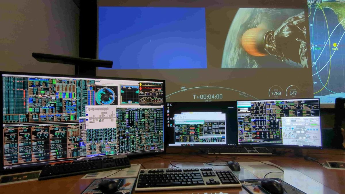 a bunch of screens in the front showing flight control data in the back is a view of a launch including a rocket firing above earh