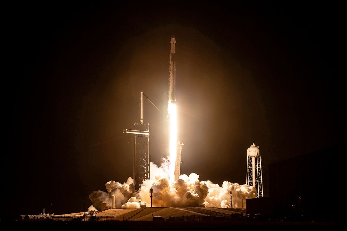 a black and white spacex rocket launches into a dark night sky