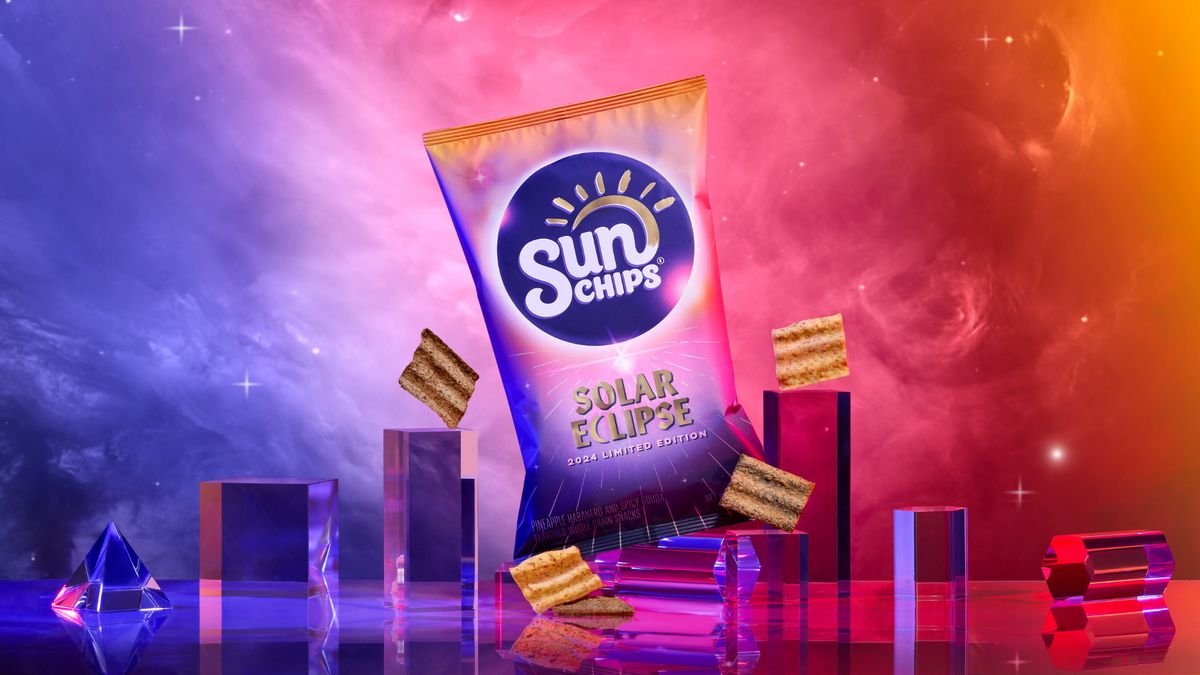 spacey gases of purple pink red and orange collide in the background A similarly colored back of SunChips stands in the middle some chips float nearby the bag is flanked on either side by transparent rectangular columns