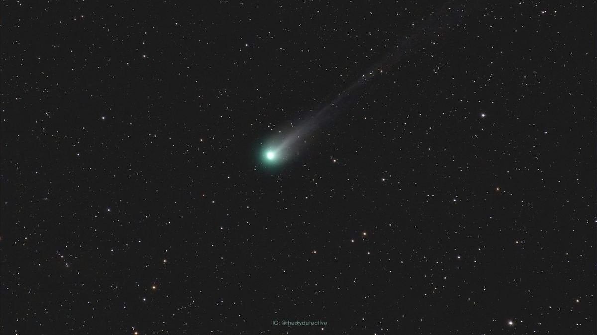Comet 12PPons Brooks with a glowing green nucleus and long tail streaking behind against a background of stars