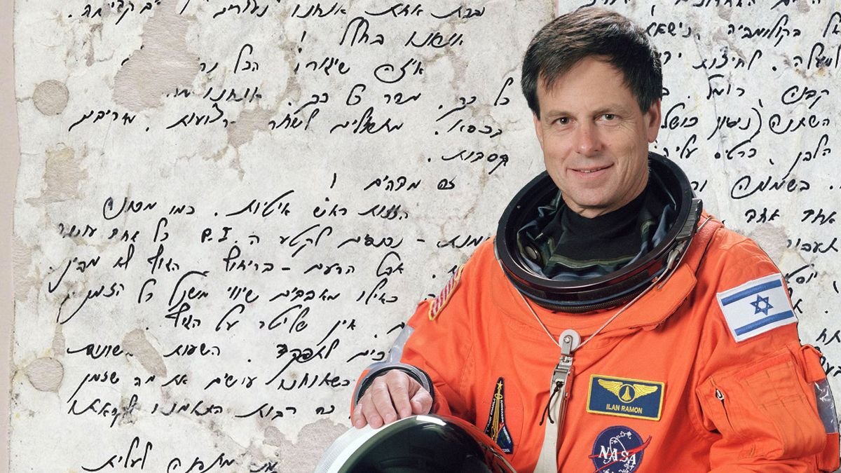 photo of a smiling man in an orange flight suit superimposed over a blown up image of a diary entry written in hebrew