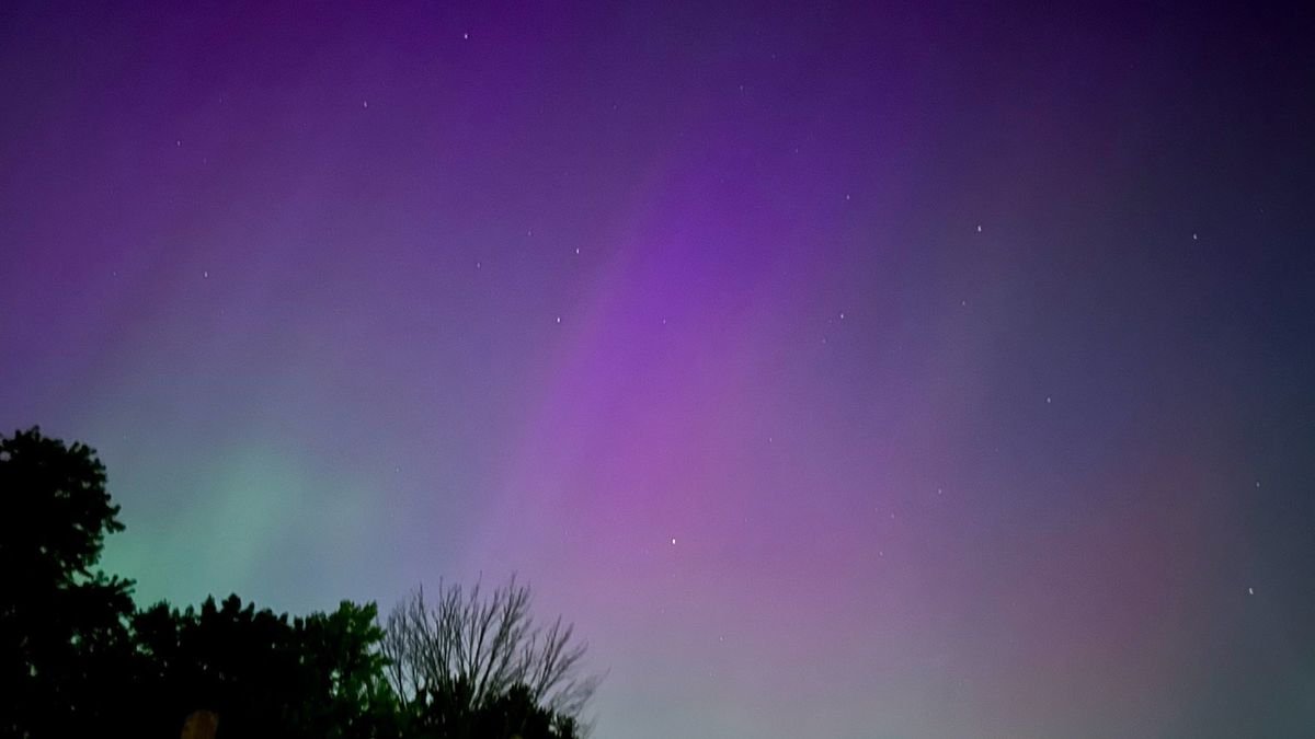 photo of the northern lights showing light green and purple lights in a dark night sky
