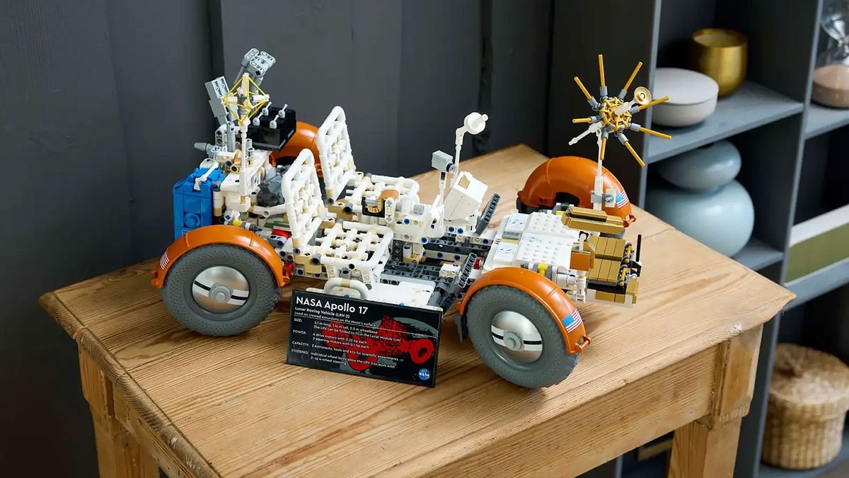 a white and orange four wheeled lego rover sits on a small wooden table