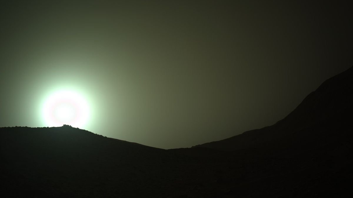 the sun rises through a red dusty haze on mars
