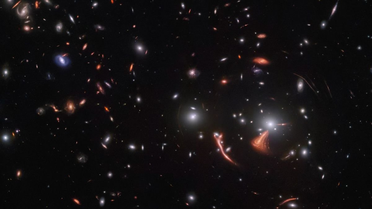 wide field telescope view showing dozens of distant galaxies
