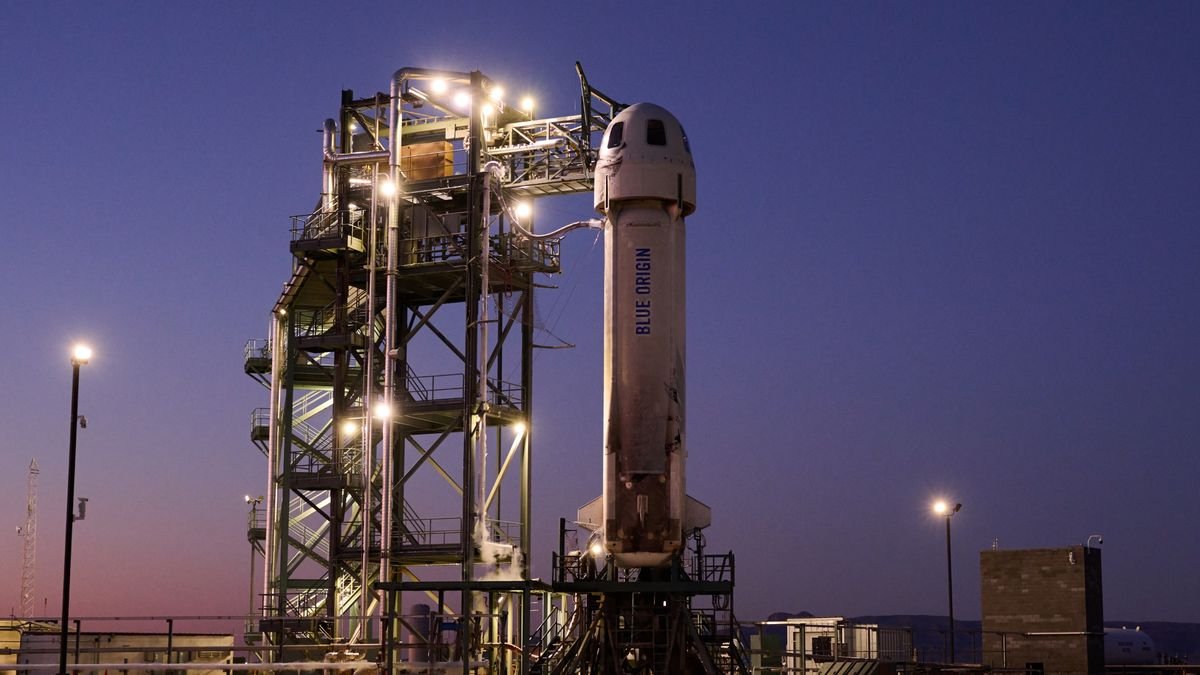 A white Blue Origin suborbital rocket stands on its launch pad at dusk in West Texas