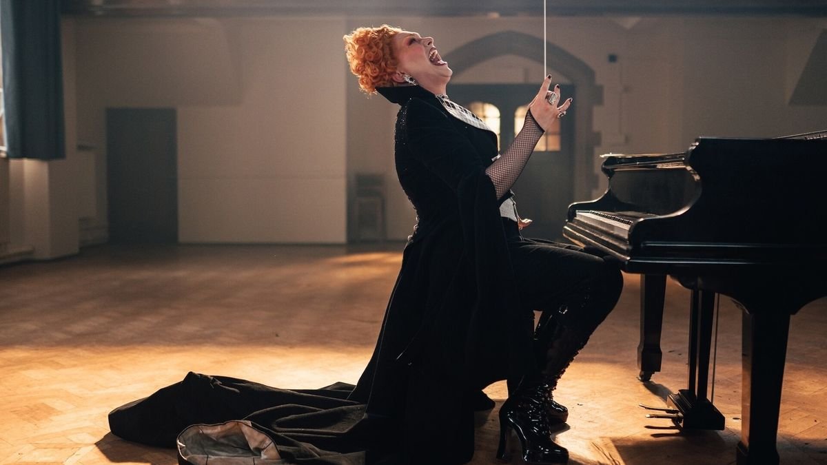 Jinkx Monsoon as the Maestro villain on Doctor Who holding a baton at a piano