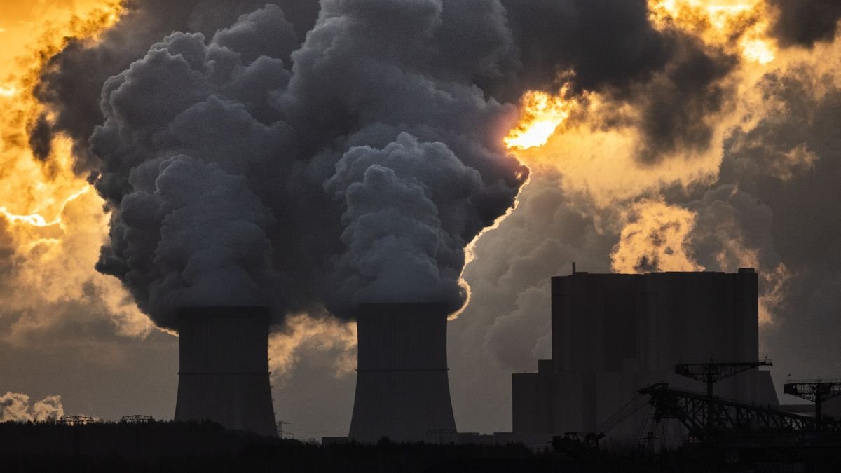 Smoke is pushed up from the towers of a power plant at sunset