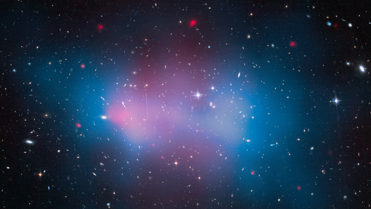 A view of space with blue and pink hazes overlaying lots of stars and galaxies