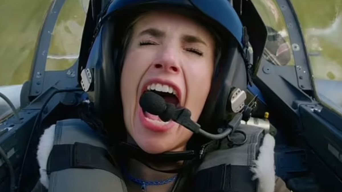 a woman in a fighter pilot helmet screams inside a cockpit