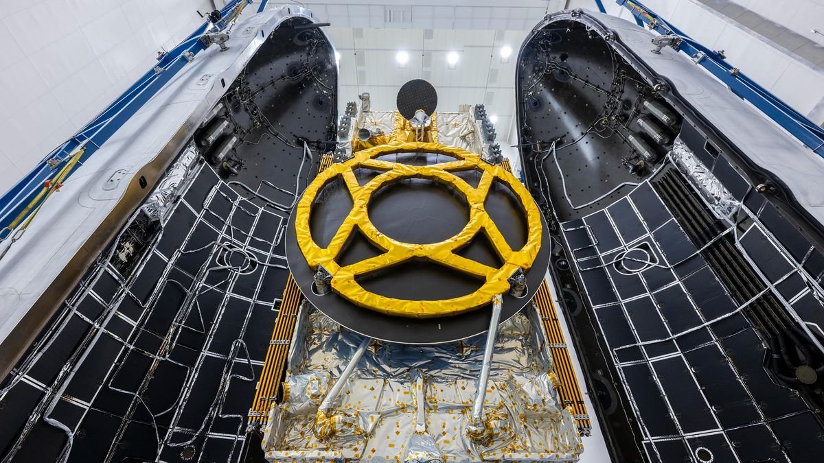 a black and yellow satellite is seen between the two halves of its rocket