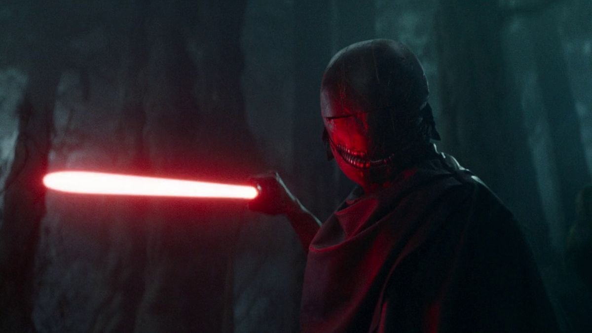 A masked villain is pointing a red lightsaber in a threatening manner