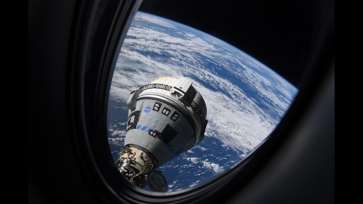 A white space capsule seen through a window in space above Earth