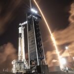 A SpaceX rocket streaks over another SpaceX rocket on the launch pad