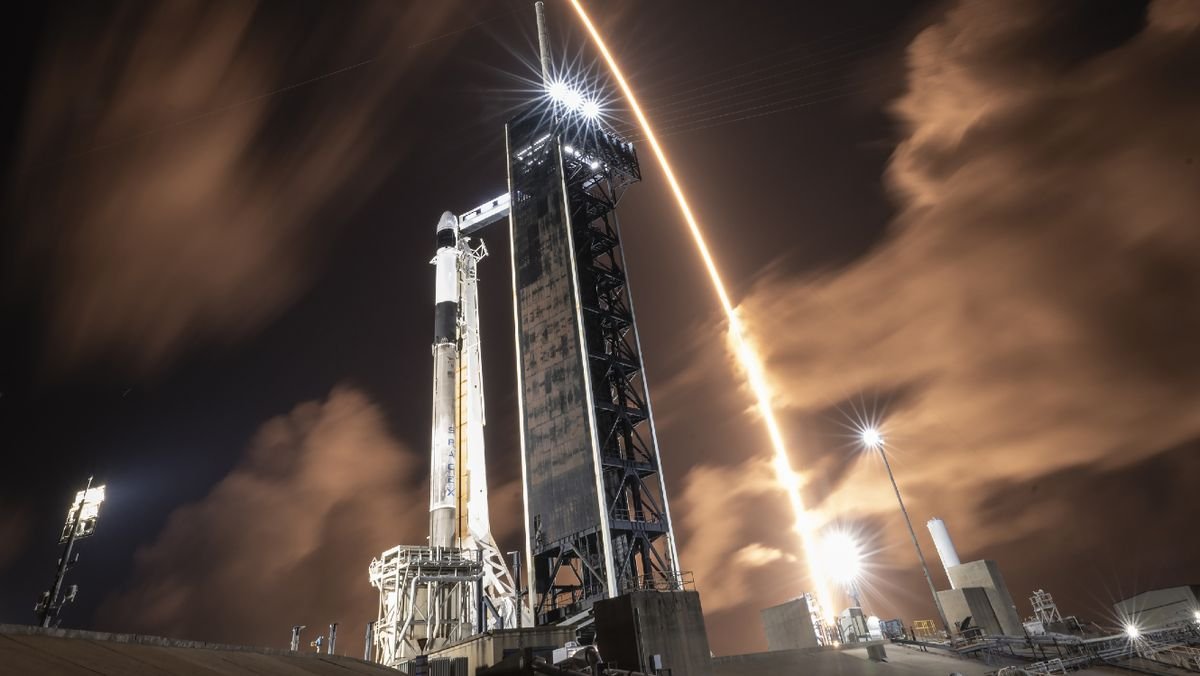 A SpaceX rocket streaks over another SpaceX rocket on the launch pad