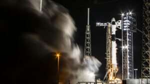 A black and white SpaceX Falcon 9 rocket fires its engines in a test on a launch pad for Crew-9