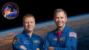 two men in blue flight suits pose for a portrait with the arms crossed in front of a background of earth as seen from space