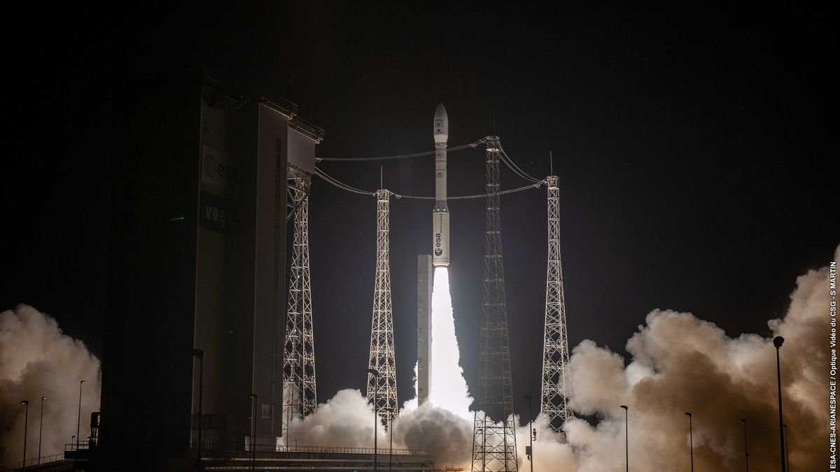 a small white rocket launches into a night sky.