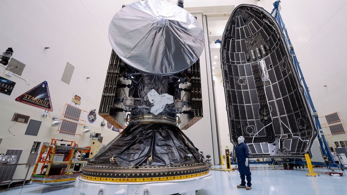 a large silver and black spacecraft is seen inside a large white hangar