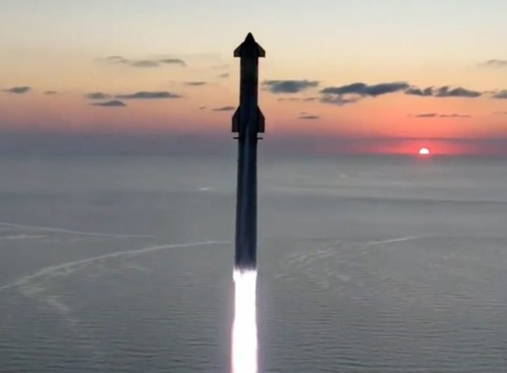 a large rocket launches into a dawn sky from a seaside pad