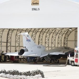 a white jet sits in a hangar in the desert