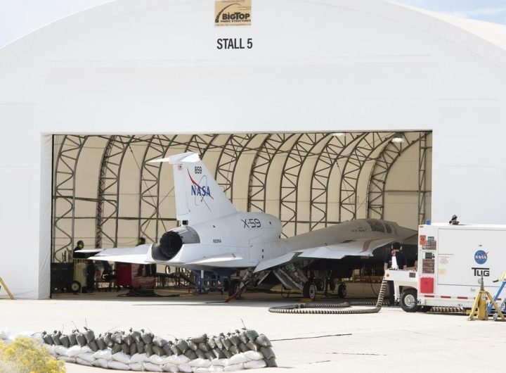 a white jet sits in a hangar in the desert