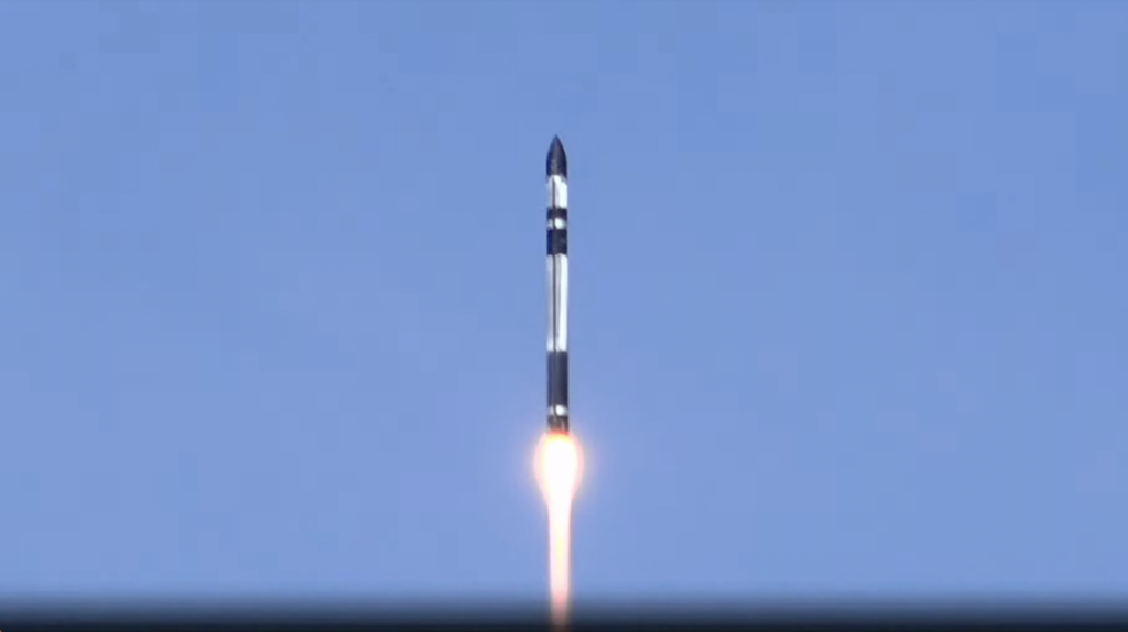 a black and white rocket launches into a blue sky