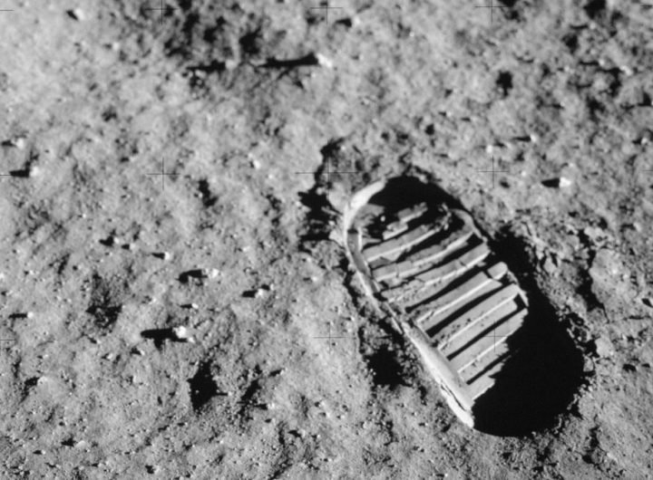 a footprint of a large clunky boot in dusty gray soil