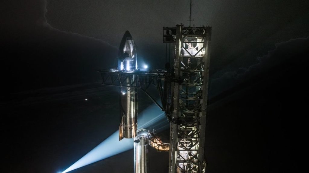 A silver stainless-steel SpaceX Starship is assembled for launch on the pad for Flight 7.