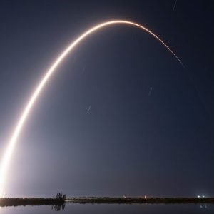 A rocket launch carves an orange arc into a dark night sky in this long-exposure photo.