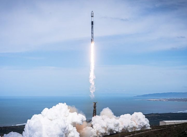 a black-and-white spacex falcon 9 rocket launches into a blue sky.